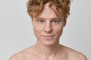 Beauty portrait of young ginger red haired shirtless male model with freckles and blue eyes natural...