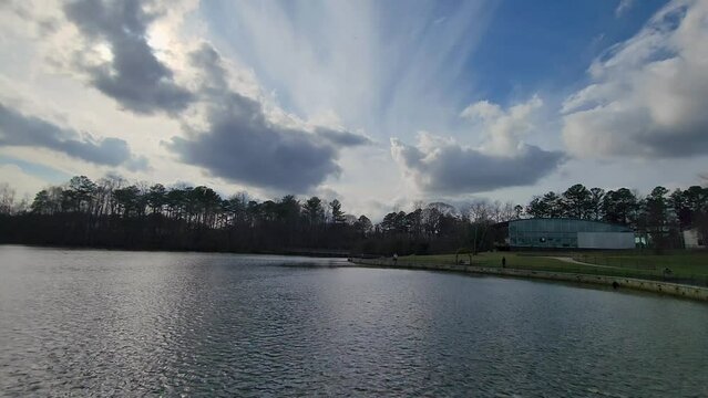 panning footage of a gorgeous landscape on the lake with lush green trees, rippling blue water, a gorgeous blue sky and clouds at Rhodes Jordan Park in Lawrenceville Georgia USA