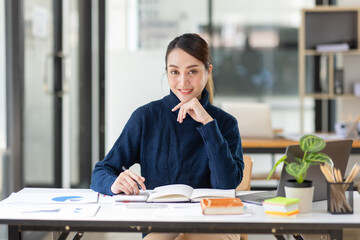 Young Asian professional business woman office worker analyst sitting at desk working on laptop...