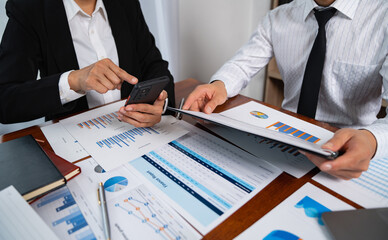 Asian businessmen use devices for business holding a smartphone and discussing administrative data analysis Marketing and Financial Growth.