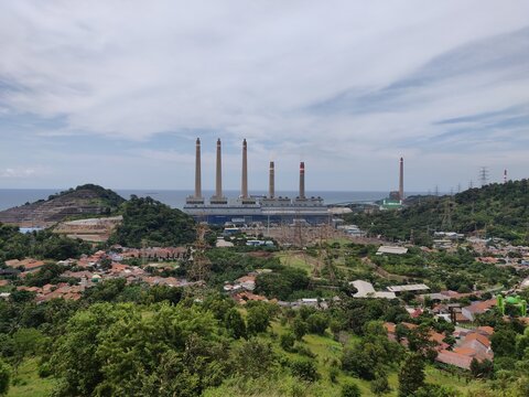 Industrial landscape with power plant chimneys and green hills in Indonesia
