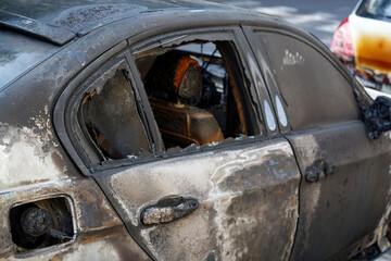 Cars burned down in the middle of the street. Windows shattered from the explosion. Burned out new car in the city street, vandalism, mafia. Setting fire to cars by vandalism and damage to property