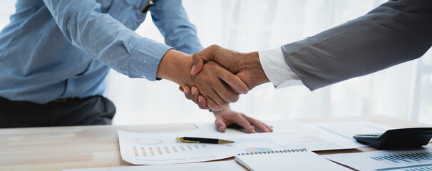 Two young Asian businessmen shake hands and agree to invest in a joint venture related to real estate. , Insurance income in the office. - obrazy, fototapety, plakaty