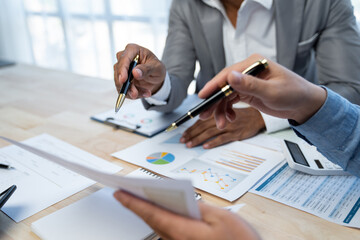 Group of Asian businessmen, and financial analysts pointing to data graphs and financial comparison...