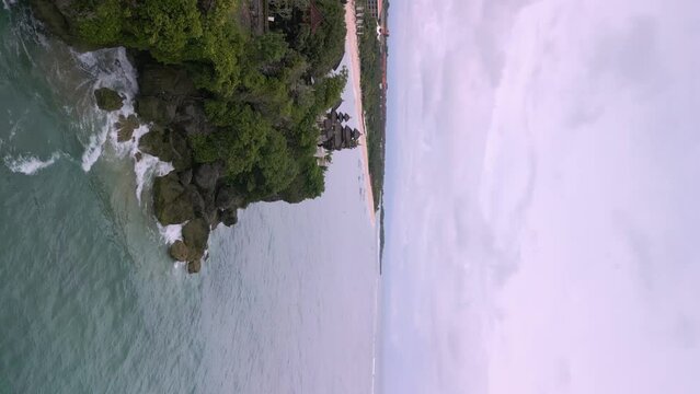 Vertical video of a hindu tempel on a ccliff above the wild blue sea in Bali