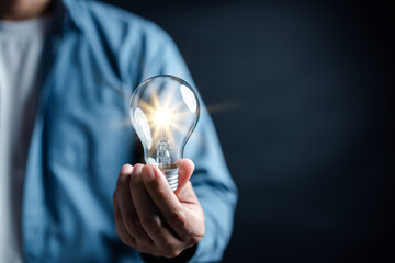 Hand man holding illuminated lightbulb, idea, innovation and inspiration with glowing virtual...