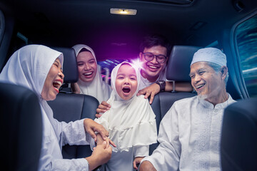 Three generation muslim family sitting in two rows of passenger seats in car - obrazy, fototapety, plakaty