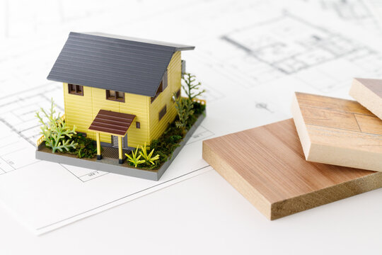 木材のサンプルと家の模型と間取り図。不動産の計画と相談イメージ