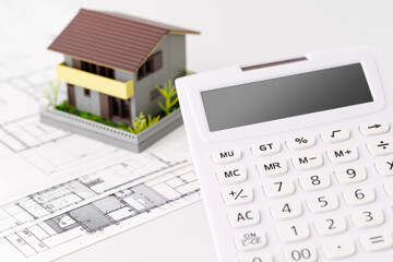 電卓と家の模型。住宅購入やリフォームの予算や見積もり