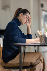 Asian women sitting in an office With stress and eye strain Tired, portrait of sad unhappy tired frustrated disappointed lady suffering from migraine sitting at the table, Sick worker concept	