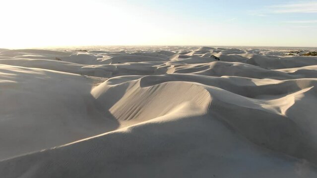 Low aerial over white smooth sand dunes in Guerrero Negro, Baja Norte, Mexico at sunset