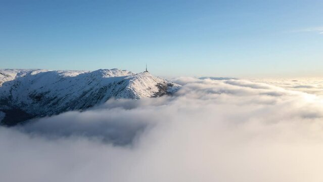 Drone shot just above inversion clouds showing a winter landscape with mountains in Bergen, Norway
