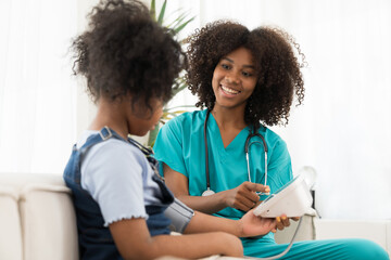 Female doctor or nurse using blood pressure gauge with child girl patient in the hospital - Powered by Adobe