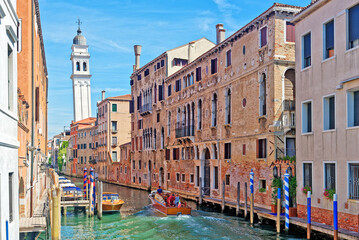 Fototapeta na wymiar Canal with boats in Venice and Greek orthodox church San Giorgio dei Greci in the background. Boats and gondolas are the main transportation means in Venice