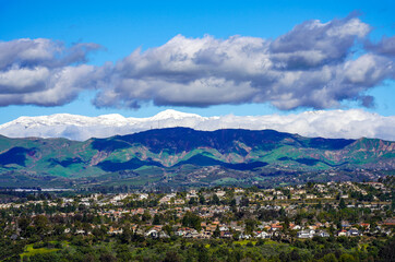 Fototapeta na wymiar Panoramic Snow capped Conejo mountains in Ventura Southern California after historic 2023 snow fall and green hills Santa Rosa Valley with homes 