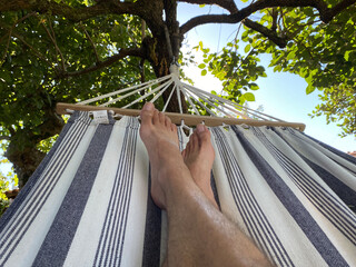 bare feet of a man lying on a hammock relaxed on vacation