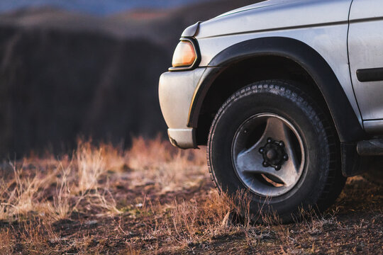 Offroader crossover car standing on mountain terrain at sunset. Travel and adventures 4wd suv with big wheel, copy space.