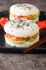 Sushi sandwich with rice, salmon, avocado and sesame close-up on a plate on the table. Vertical