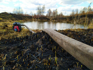 Electric water pump placed on the pond coast. Portable water pump on country pond coast. extinguishing a natural fire. burning soil and vegetation. peat fire.