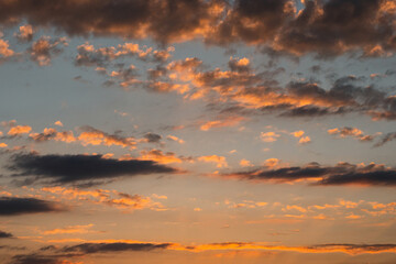 A summer sunset in yellow and orange. The sun's rays from below illuminate the dark clouds. The beauty of the wildlife.