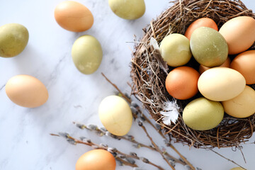 Top view of a nest of twigs inside with yellow, green and light green easter eggs