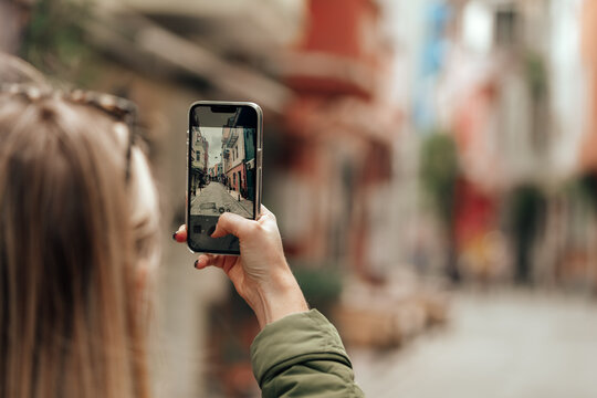 Woman taking photo with phone in the street back view