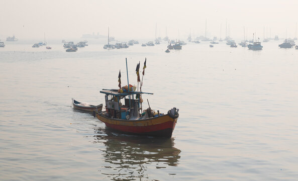 Colorful fishing boats near the shore of dirty water of Arabian sea at amazing sunrise - Mumbai, India