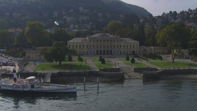 Low aerial dolly towards Olmo Villa on the shores of the stunning Lake Como, Italy
