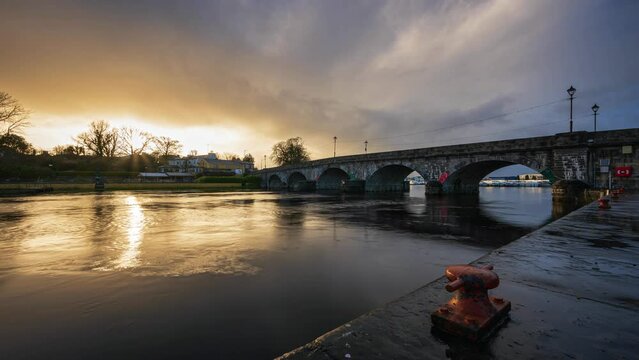 Timelapse of Carrick on Shannon town bridge in county Leitrim and Roscommon with traffic, people and moving shower sunset evening clouds on river Shannon in Ireland.