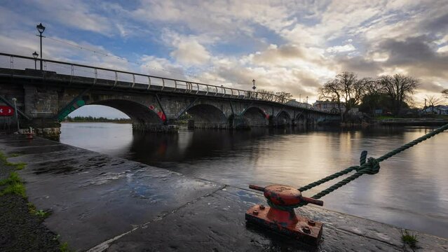 Timelapse of Carrick on Shannon town bridge in county Leitrim and Roscommon with traffic, people and moving sunset evening clouds on river Shannon in Ireland.