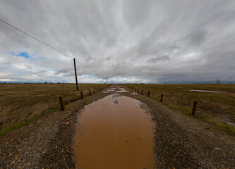 Dirt road with potholes filled with water 