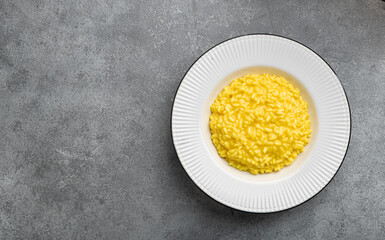 Traditional Italian dish Risotto alla milanese on a concrete background, top view, copy space