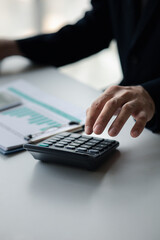 Business man using a calculator to calculate numbers on a company's financial documents, he is analyzing historical financial data to plan how to grow the company. Financial concept.
