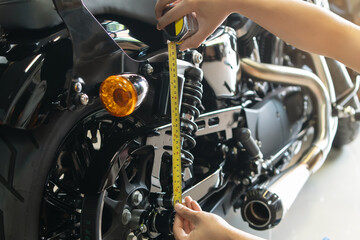 mechanic using tape measure set up suspension sag Compression and Rebound on motorcycle at garage, ...