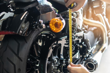 mechanic using tape measure set up suspension sag Compression and Rebound on motorcycle at garage,  repair and maintenance motorcycle concept .selective focus