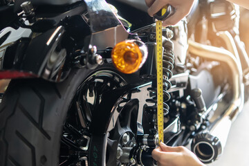 mechanic using tape measure set up suspension sag Compression and Rebound on motorcycle at garage, ...