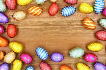 Colored chocolate Easter eggs on a wooden background. Top view. Copy space.