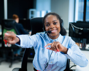 Young african woman talking to a client on a headset. Happy female call center employee. 