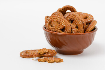 Shaped rye o cocoa cookies or pretzels in brown clay bowl isolated on white background