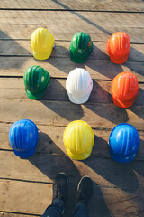 Safety helmet (hard hat) for engineer, safety officer, or architect, place on wooden floor. Yellow, White, green, blue, and orange safety hat (helmet) on construction site-Vertical image.