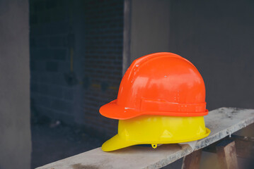 Safety helmet (hard hat) for engineer, safety officer, or architect, place on wooden floor. Yellow...