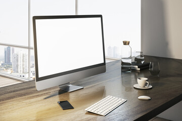 Perspective view on blank white modern computer monitor with place for web design or web page on stylish wooden table with keyboard and coffee mug on sunlit city view background. 3D rendering, mock up