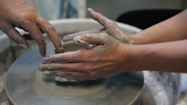 Young woman artist making clay bowl on pottery wheel