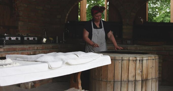 Old Woman Baker Preheating The Traditional Round Clay Oven In Kakheti, Georgia. - Medium Shot, Slow Motion