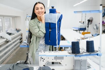 Fototapeta premium Happy female dressmaker working with sewing machine at textile factory.
