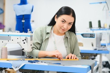 Young woman working as seamstress in clothing factory.