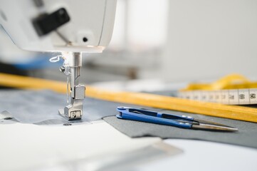 Composition of sewing thread, scissors and tape measure on a white table. Concept of a clothing designer