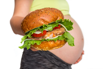 Pregnant woman with belly is holding a burger