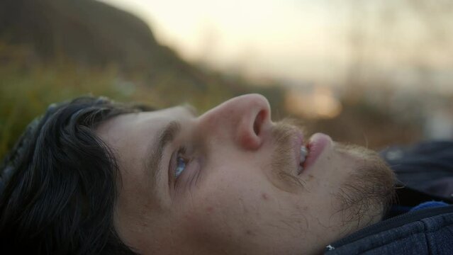 Close-Up Relaxing in the Heart of Nature: Handsome Young Man Taking a Deep Breath and Resting Amidst the Grasslands
