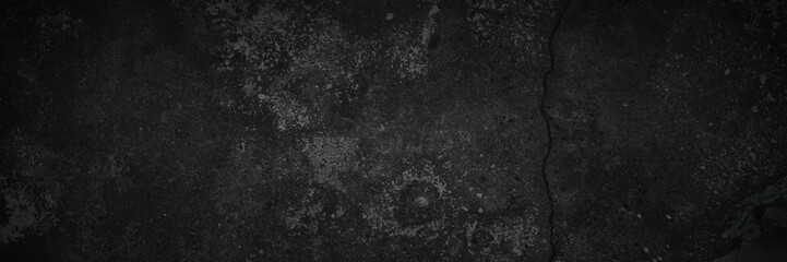 Texture of old cracked concrete wall. Rough dark gray concrete surface with spots, cracks, noise and grain. Dark wide panoramic background for design. Shaded texture with vignette.